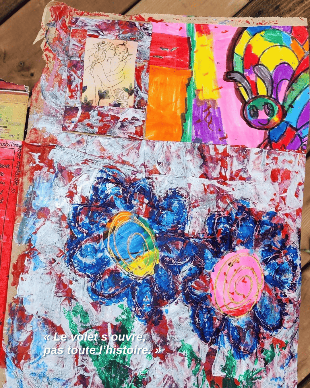 Photographie d’un carnet ouvert sur une création intuitive aux tons rouge, bleu et argenté. Un volet de fenêtre ouvert révèle une maman serrant son enfant dans ses bras, près d’un papillon multicolore et de grandes fleurs bleues.